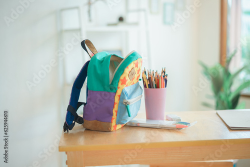 School backpack on wooden bench and home in the background
