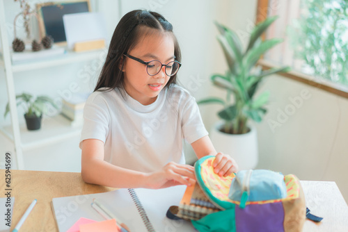 Pupil child put books and notes into backpack. School supplies.Back to school concept. Kid prepare for studies. Portrait cute little girl packing backpack .