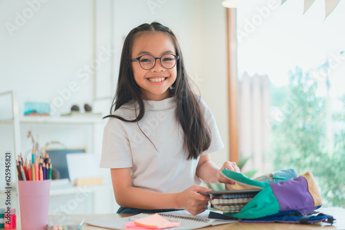 Pupil child put books and notes into backpack. School supplies.Back to school concept. Kid prepare for studies. Portrait cute little girl packing backpack .