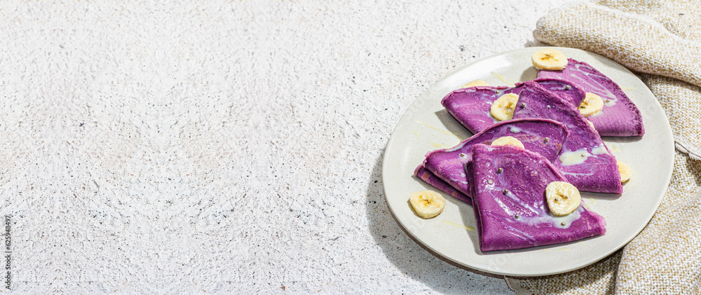 Thin lavender pancakes with banana slices and sweet topping. Healthy vegan non lactose food Thin lavender pancakes with banana slices and sweet topping. Healthy vegan non lactose food