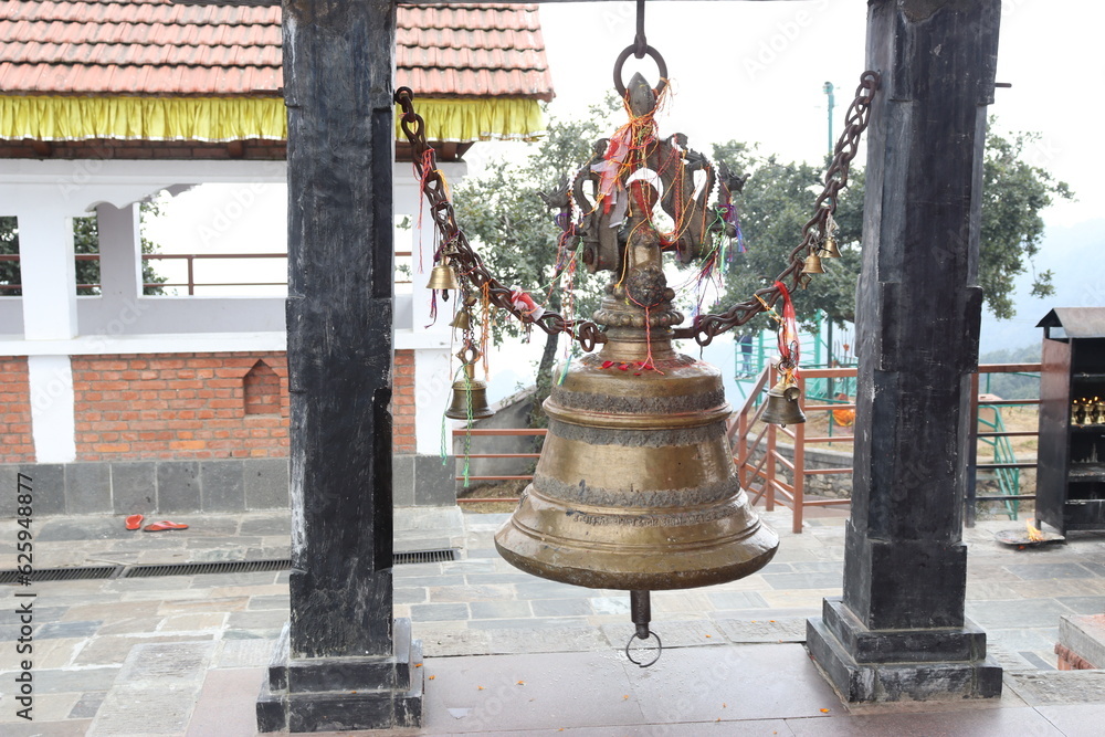 Obraz premium Close up view of a temple bell made up of bronze material, hanged in between two pillars