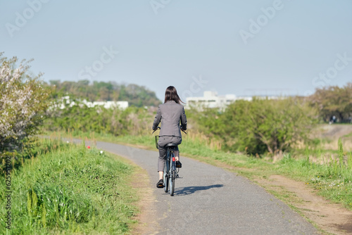 自転車に乗って通勤する女性の後ろ姿
