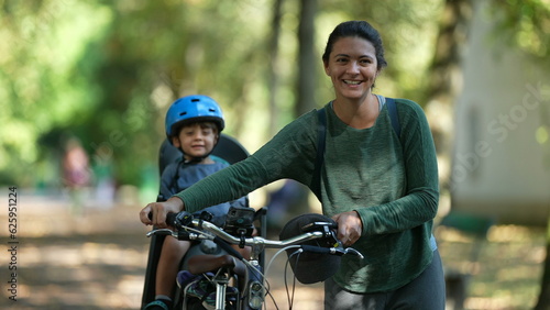Happy mother and child outside carrying bike toddler in bicycle back seat
