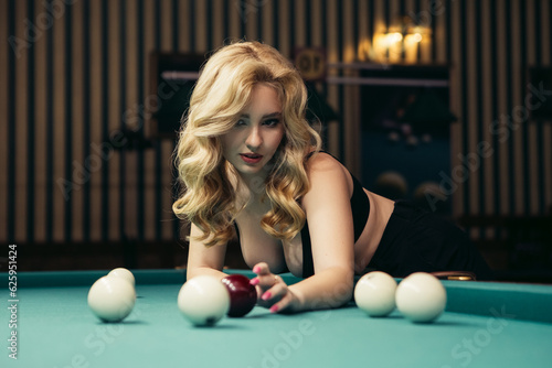 Blond woman playing enjoying billiard, hold billiard balls on table with green surface in billiard club. Pool game snooker pyramid player

 photo