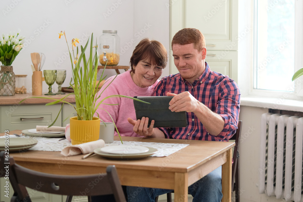 Digital Interaction Across Generations: An intriguing blurred image of a young man and a senior woman engaged in a technological journey on a tablet