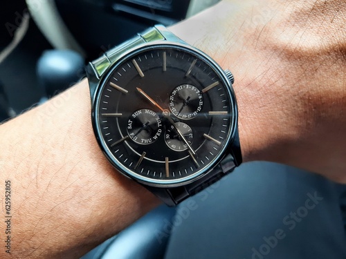 Man left hand wearing an analog black watch in the car