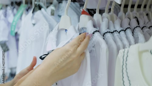 Close-up of a woman looking at a school blouse in a store