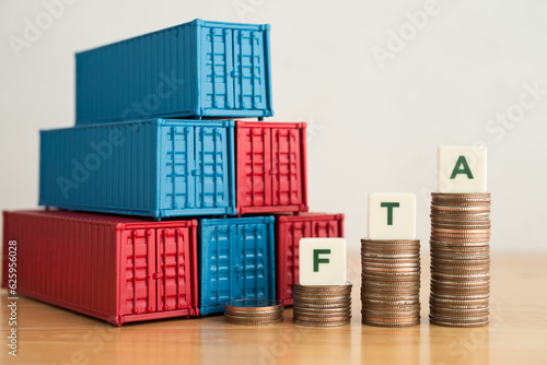 Shipping containers and stacked coins as graph chart growth with FTA letters on wooden tablw white wall background. Concept of free trade agreement (FTA), global trade, investment, cargo shipping. photo