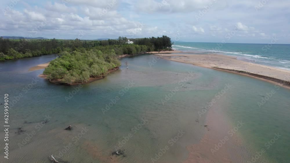 A sandy beach separates the ocean and the river. Aerial view from the drone of the ocean waves, white clouds in the sky and a calm river with clear water. Rainforest. There is a house. Thailand A sandy beach separates the ocean and the river. Aerial view from the drone of the ocean waves, white clouds in the sky and a calm river with clear water. Rainforest. There is a house. Thailand