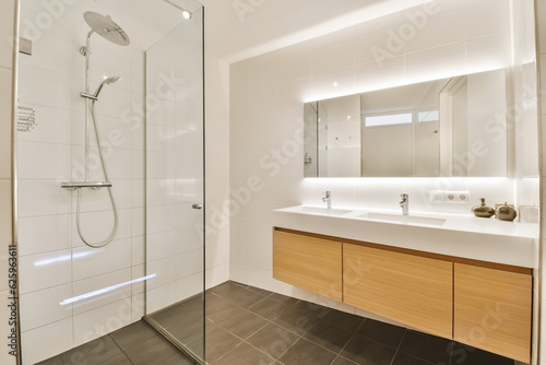 a modern bathroom with wood cabinets and white tiles on the walls  along with a walk - in shower stall