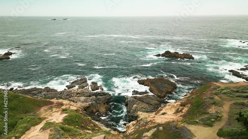Coast of highway 1 on summer overcast day. Ocean waves hitting the rocky shore.