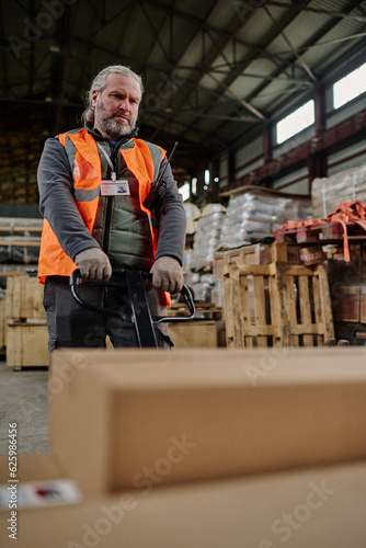 Vertical image of warehouse worker loading containers in storage room