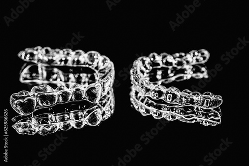 Invisible aligners retainers of teeth lie on the mirror on a black and white photograph