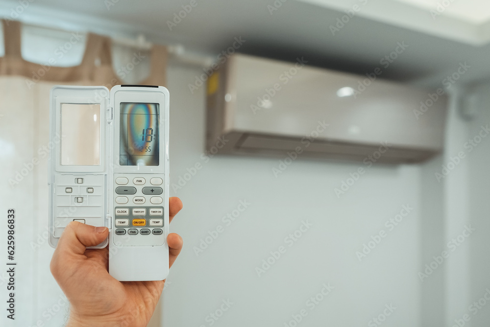 Hand holding remote control in front of the air conditioner. Hand holding remote control in front of the air conditioner.