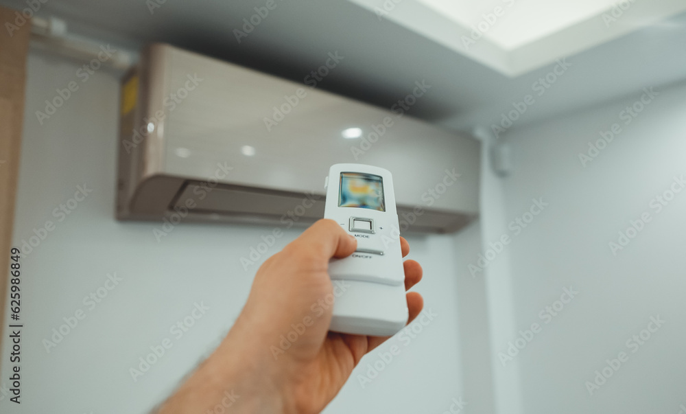 Hand holding remote control in front of the air conditioner. Hand holding remote control in front of the air conditioner.