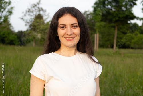 Portrait of a 35-year-old brunette woman looking at the camera smiling in nature.