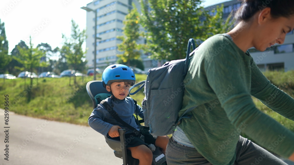Mother riding bicycle with little boy sitting on back seat Mother riding bicycle with little boy sitting on back seat