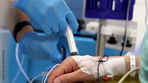 4K close up footage of nurse injecting antibiotic to patient's IV drip. Patient bandaged hand and nurse hands in glow stock video.