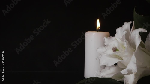 candle on black background with lily flower