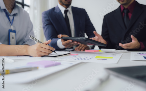 Business documents on office table with smart phone and calculator digital tablet and graph business with social network diagram and two colleagues discussing data working in office