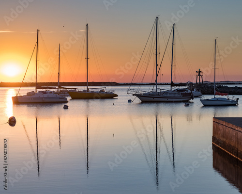 Sunset in the port of Juan Lacaze, with several sailboats anchored in the foreground photo