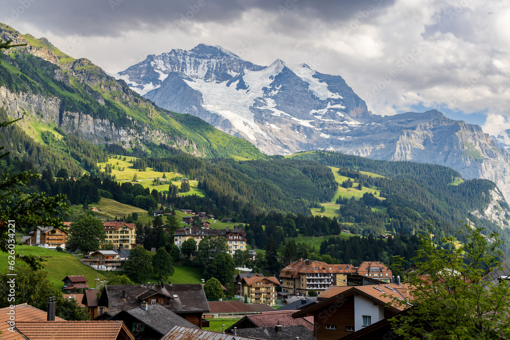 A view of the Swiss Alps and the village of Lauterbrunnen in the Berner Oberland area of Switzerland, with mountains in the background, a valley and chalets in the foreground