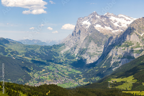 The small village of Grindewald as seen from a hiking trail in Switzerland with blue skies and a mountain in the background