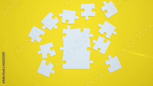 The puzzle is assembled and disassembled on yellow background, top view. Stop motion animation