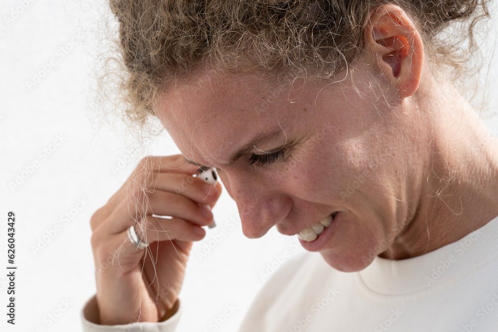Obraz premium woman smiling and puts an airpod in the ear wirless headphones 