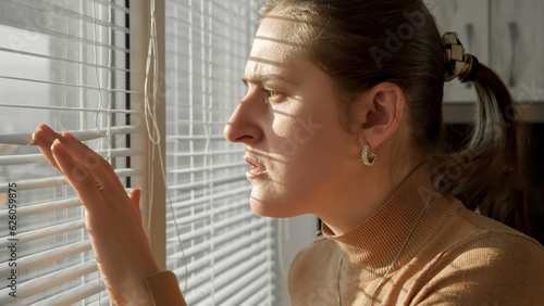 Fotografie Portrait of shocked scared woman looking outdoors through window