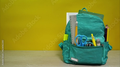 Full of school accessories schoolbag on the desk. Animation of opening backpack with school items. Back to school concept