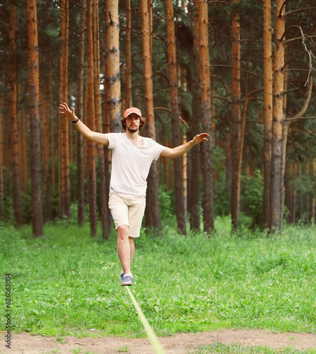 Принти на полотні Young man balancing his arms walk on a loose rope tied between two trees, male t