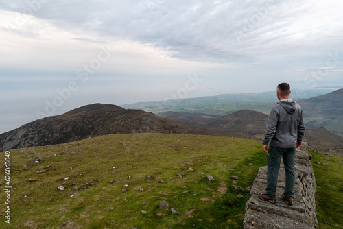Panoramic view of typical Irish landscape  fields  sea in background. Picture taken from the top of the mountain. Hiker enjoing view after sunset