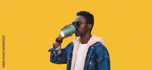 Portrait of stylish young african man drinking coffee isolated on yellow background