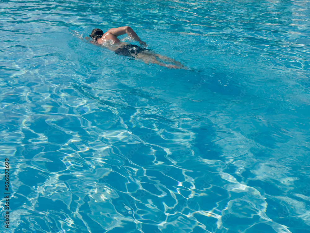young boy swimming in the pool , moving under the water in the pool