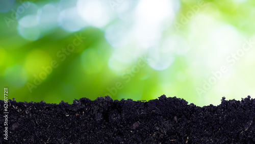 Heap of potting fertile black soil with green bokeh background, growing and organic plants ecology concept