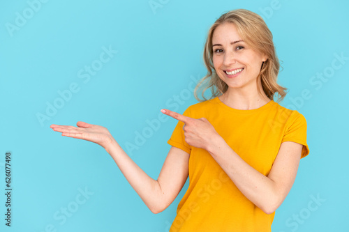 Woman holding invisible product on hand, pointing with finger at object