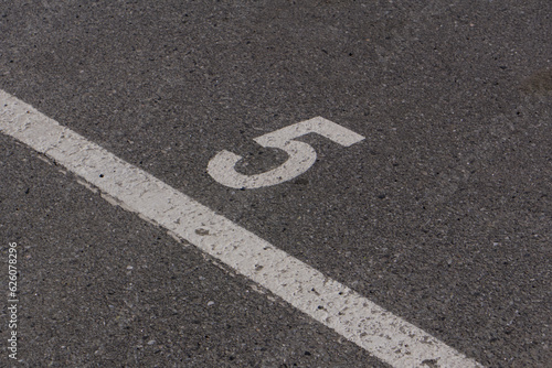 a number 5 painted on asphalt parking spot