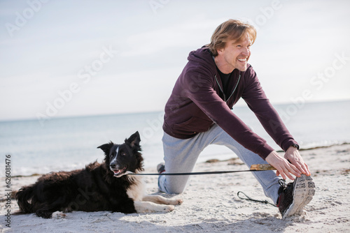 Mature man working out with his border collie dog on the beach © Geber86