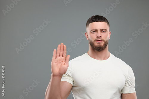 Man showing stop gesture on grey background. Space for text