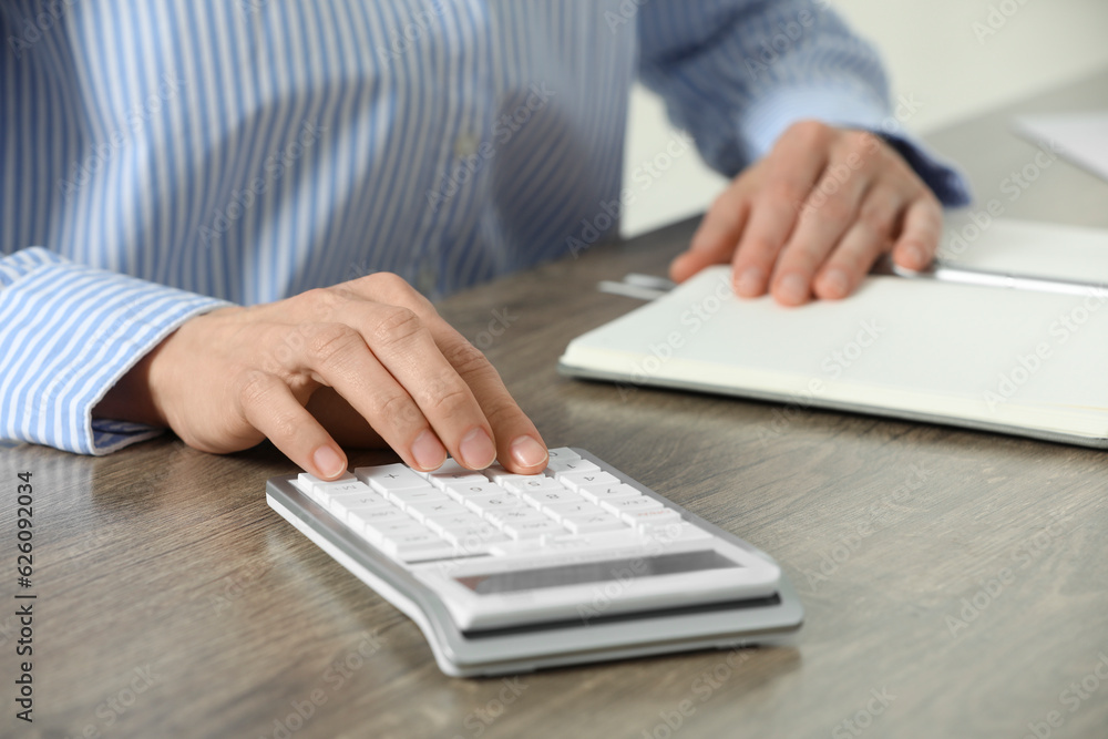 Professional accountant using calculator at wooden desk in office, closeup Professional accountant using calculator at wooden desk in office, closeup
