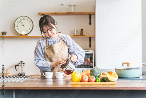 朝キッチンでコーヒーを淹れるエプロン姿のアジア人女性 