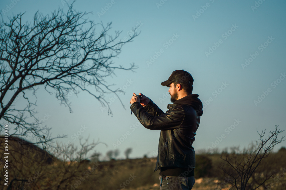 Fototapeta premium young man taking a picture of a mountain landscape