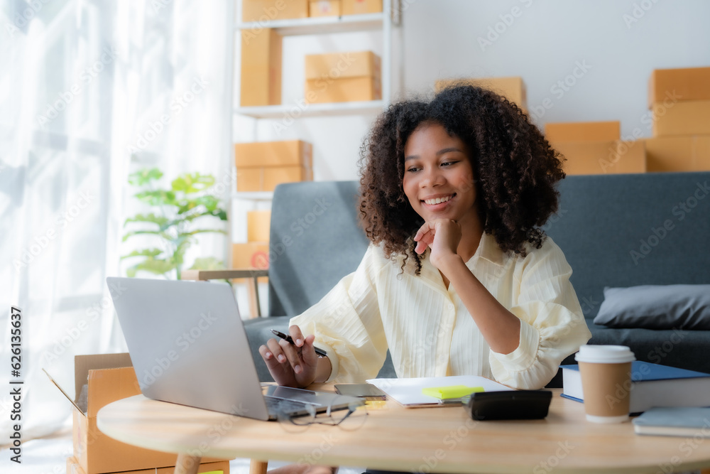 Smiling young business owner woman prepare parcel box and check online orders of product for deliver to customer on laptop computer at home. Shopping Online concept. Startup small business SME. Smiling young business owner woman prepare parcel box and check online orders of product for deliver to customer on laptop computer at home. Shopping Online concept. Startup small business SME.