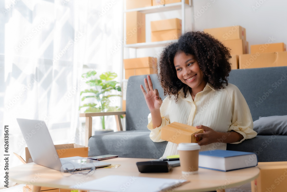 Smiling young business owner woman prepare parcel box and check online orders of product for deliver to customer on laptop computer at home. Shopping Online concept. Startup small business SME. Smiling young business owner woman prepare parcel box and check online orders of product for deliver to customer on laptop computer at home. Shopping Online concept. Startup small business SME.
