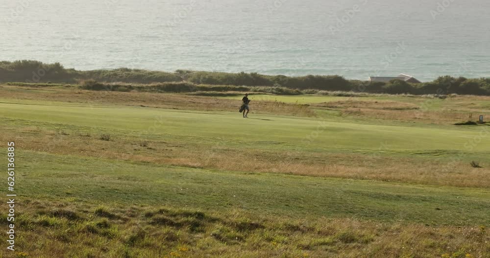 Static shot of a golfer walking across the course to head to play his ball Static shot of a golfer walking across the course to head to play his ball