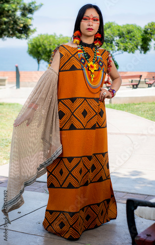 beautiful young peruvian woman of the yanesha culture posing with dresses, jewelry, makeup, clothes and accessories designed with Asháninka iconography in nature