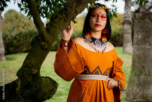 beautiful young peruvian woman of the yanesha culture posing with dresses, jewelry, makeup, clothes and accessories designed with Asháninka iconography in nature photo