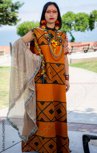 beautiful young peruvian woman of the yanesha culture posing with dresses, jewelry, makeup, clothes and accessories designed with Asháninka iconography in nature