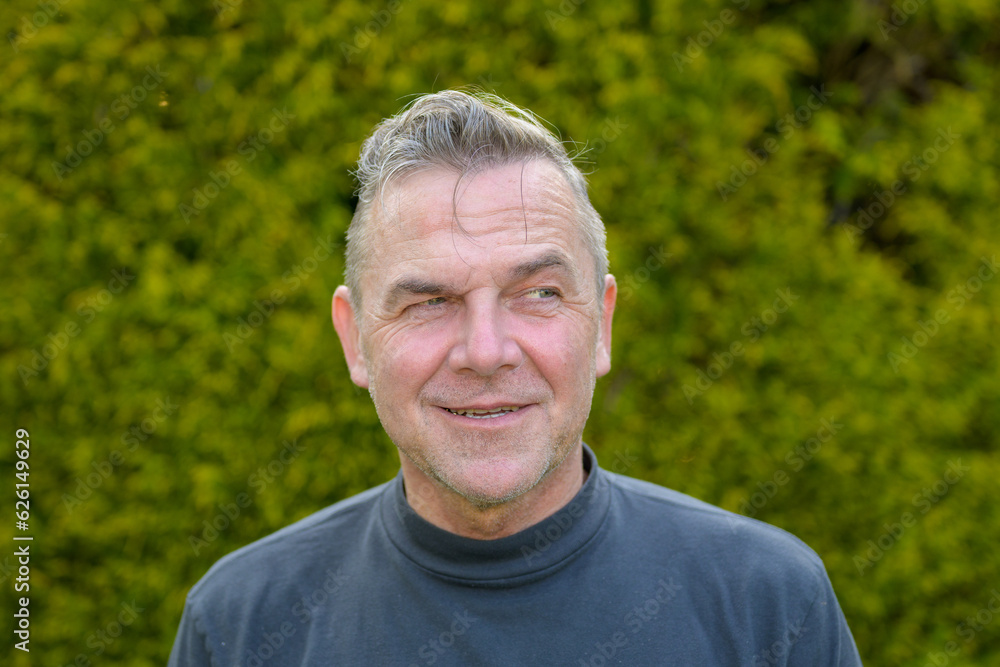 Portrait of a middle-aged man with gray hair standing in the garden Portrait of a middle-aged man with gray hair standing in the garden
